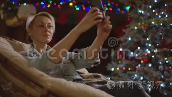 在圣诞夜，金发女人在智能手机上自拍