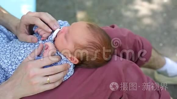 白人父亲和一个新生婴儿坐在公园里。 父母把一个摇摆不定的孩子女儿儿子抱在怀里。 真正的
