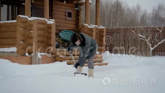 从白雪看木屋背景的冬场男子清洁铲