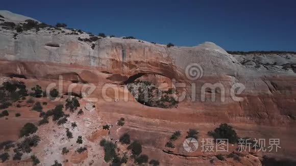 令人惊叹的空中淘沙镜头令人难以置信的洞在岩石山，游客探索惊人的拱门在国家公园。