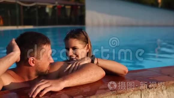年轻夫妇正一起在游泳池里游泳。