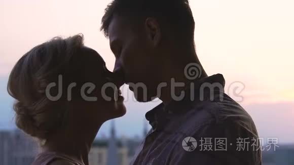年轻夫妇在天空城市风景背景下接吻，青春的爱情，相聚