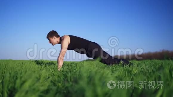 年轻人做俯卧撑,手臂伸出来锻炼身体. 英俊的白种人. 绿草如茵.