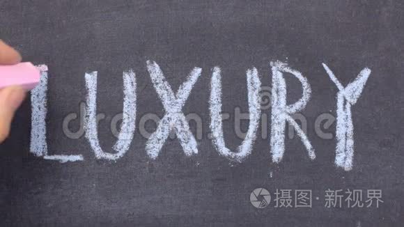 单词LUXURY，用粉笔在黑板上手写。
