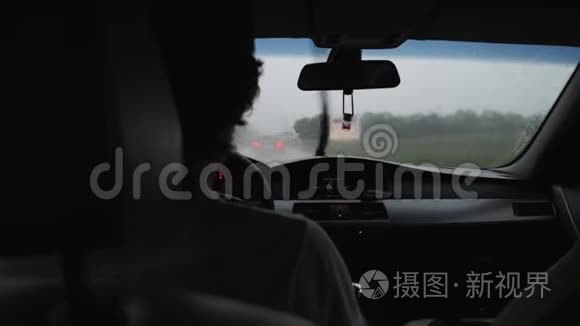 在雨中开车的人在挡风玻璃上滴着水