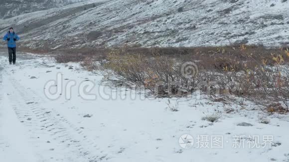 一个人在山里旅行。 他走在下雪的路上。