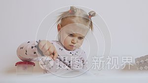 一个小女孩坐在桌子旁集中精力在纸上画水彩