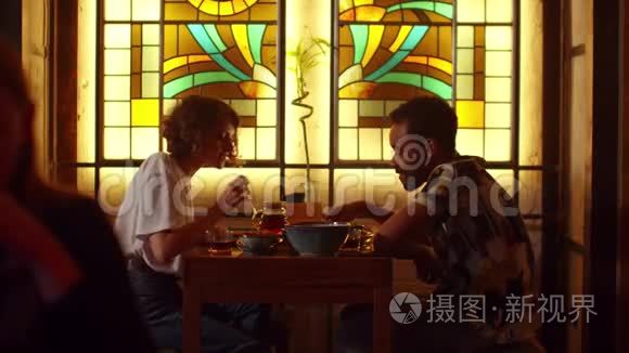 两个人坐在咖啡馆的桌子旁，聊天吃东西