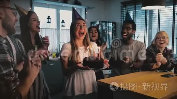 快乐兴奋的白种人女孩拿着生日蛋糕，多民族的朋友在有趣的聚会上唱着欢快的歌慢动作。