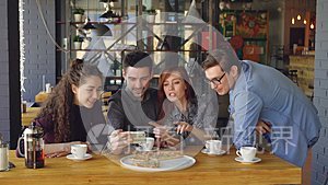 年轻人正在玩视频聊天，手里拿着智能手机，看着网络摄像头，在漂亮的咖啡馆里和朋友聊天