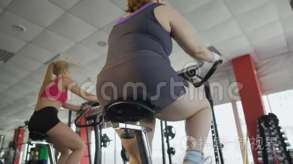 在健身房里，一个腿粗的女人骑着固定的自行车，减肥