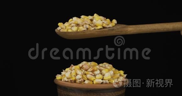 玉米粒从一个木勺上得到足够的睡眠在一堆种子在一个粘土碗。
