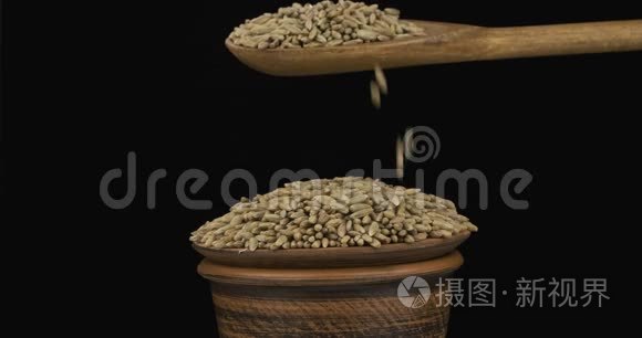 黑麦粒从一个木勺上得到足够的睡眠在一堆种子在一个粘土碗。