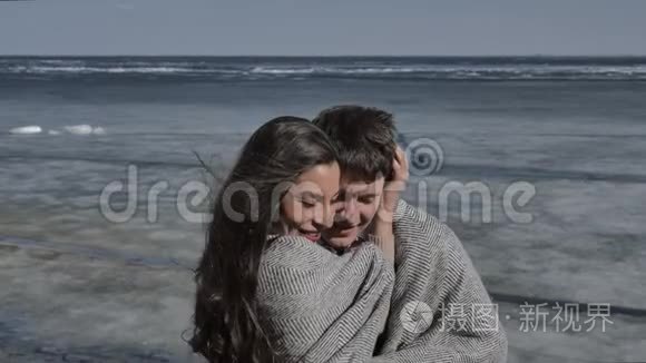 年轻夫妇拥抱着，背景是一条覆盖着冰的河流，阳光明媚的春天