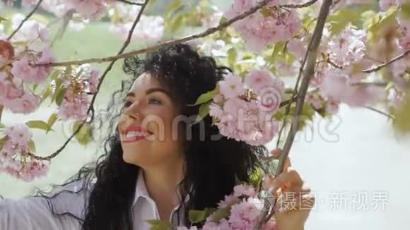 美丽微笑的黑发喜欢樱花的味道视频